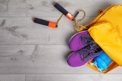 Photo of Sports bag with gym equipment on wooden background, top view