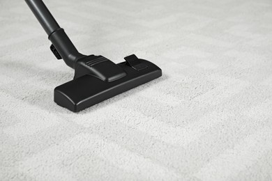 Photo of Removing dirt from white carpet with modern vacuum cleaner. Space for text