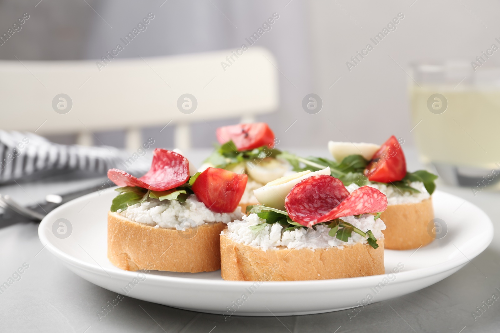 Photo of Delicious bruschettas with sausage and cheese on grey kitchen table, closeup