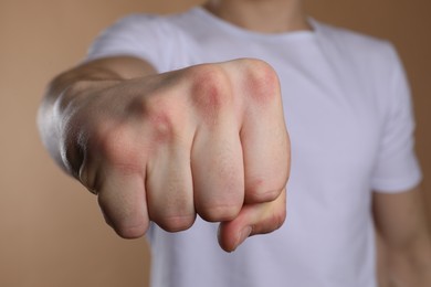 Man showing fist with space for tattoo on beige background, selective focus