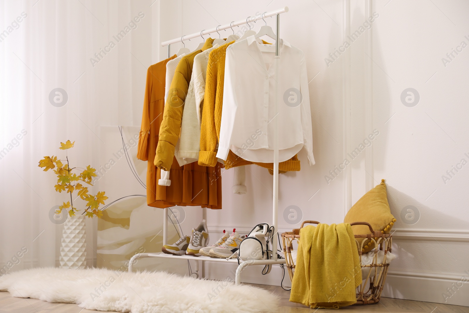 Photo of Rack with stylish warm clothes, shoes and accessories in modern dressing room