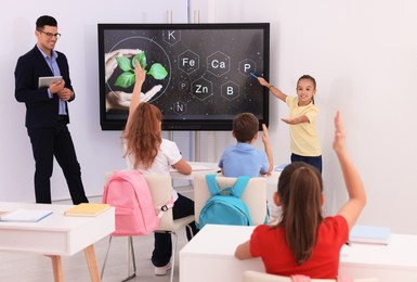 Photo of Teacher and pupil using interactive board in classroom during lesson