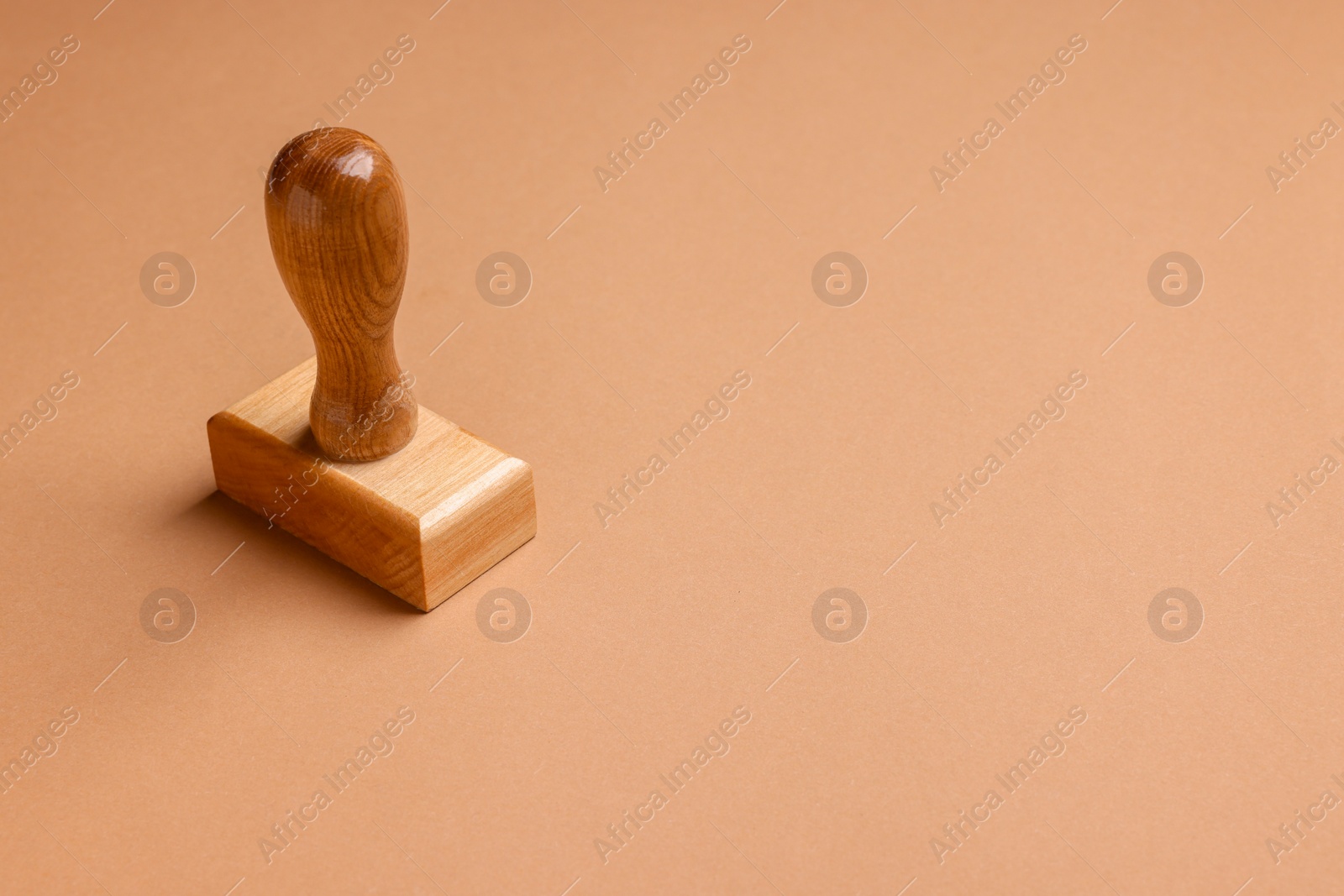Photo of One wooden stamp tool on light brown background, space for text