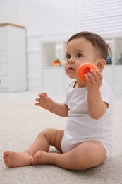 Photo of Cute baby boy playing with toy on floor at home