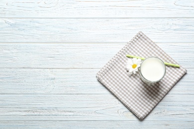 Glass of milk and flower on wooden background, top view