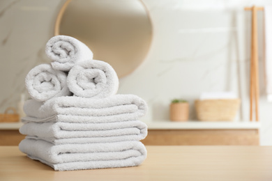 White towels on wooden table in bathroom. Space for text