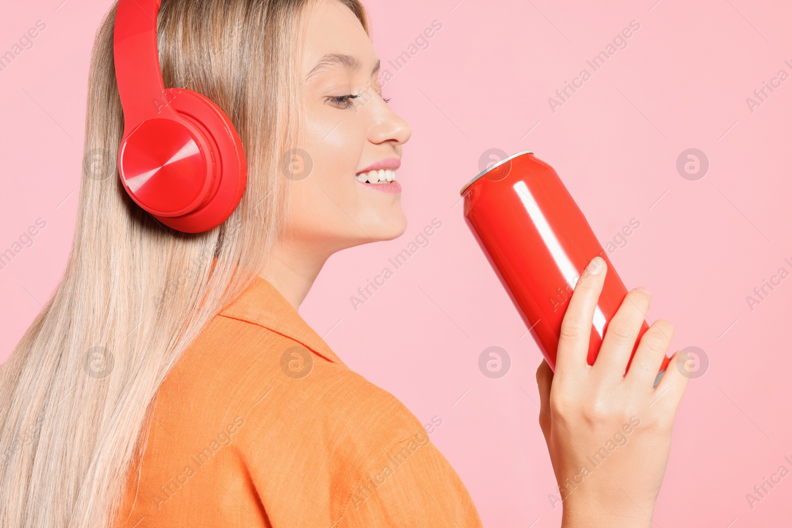Photo of Beautiful happy woman holding red beverage can on pink background