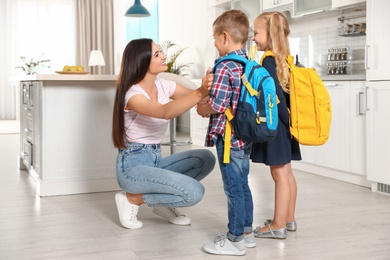 Happy mother and little children with school bags in kitchen