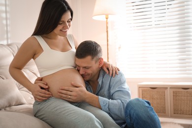 Man touching his pregnant wife's belly at home