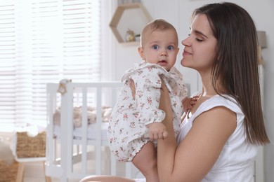 Photo of Happy young mother with her baby daughter in nursery. Space for text