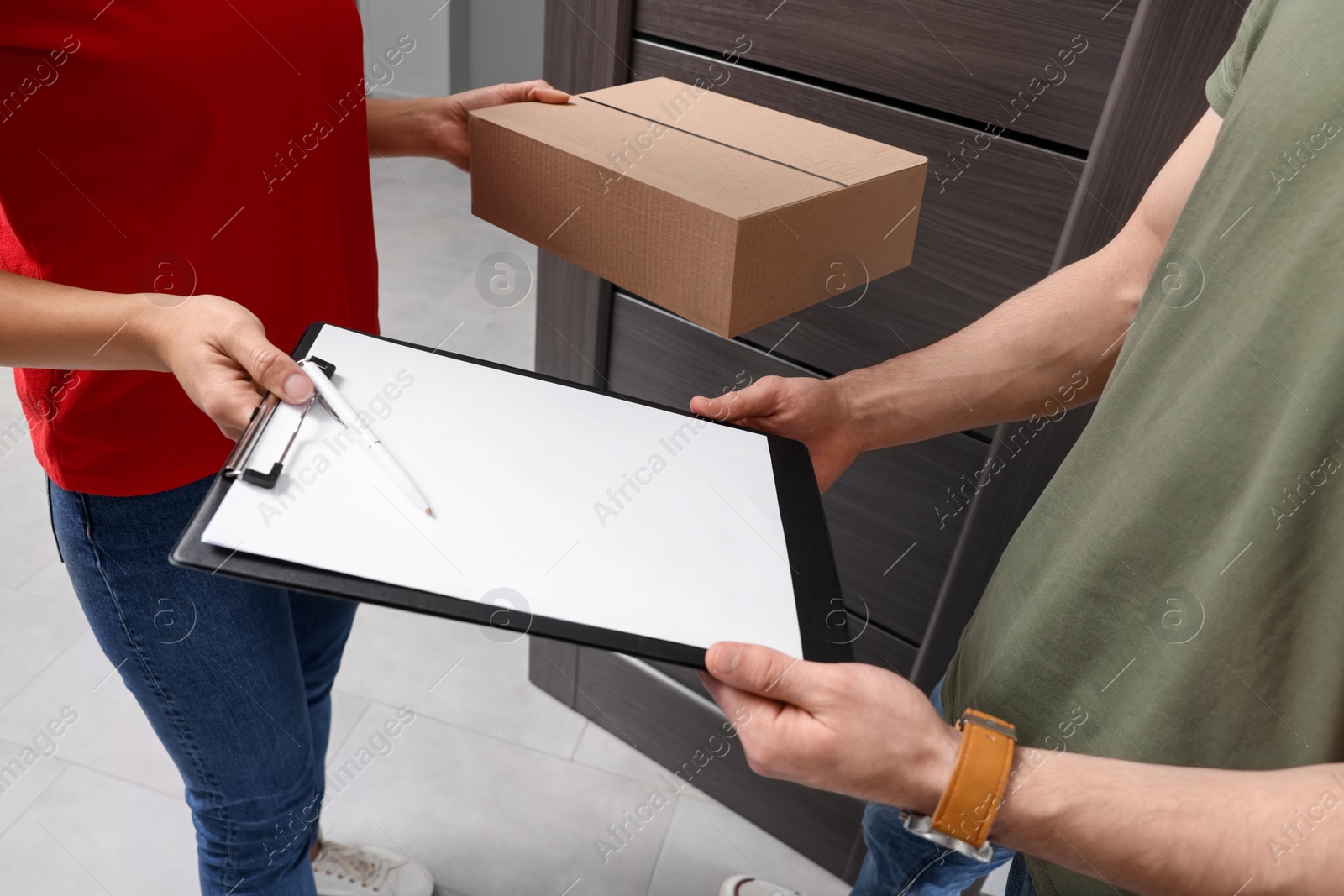 Photo of Man receiving parcel from courier indoors, closeup