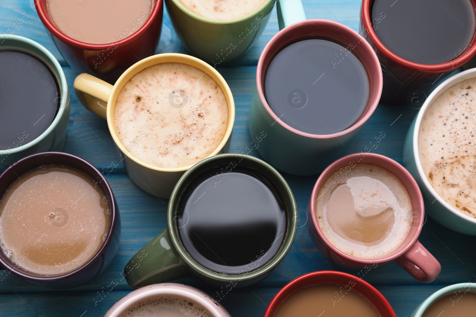 Photo of Many cups of different coffee drinks on light blue wooden table, above view