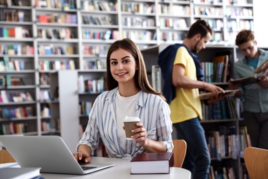 Young woman studying at table in modern library