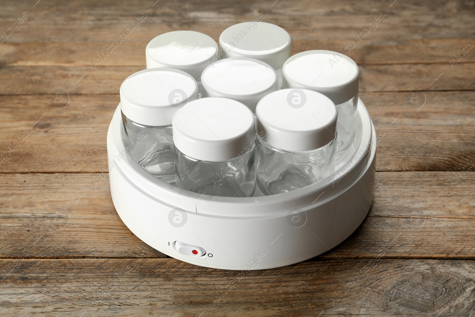 Photo of Modern yogurt maker with empty jars on wooden table