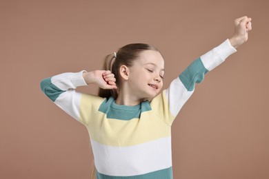 Photo of Happy little girl posing on light brown background