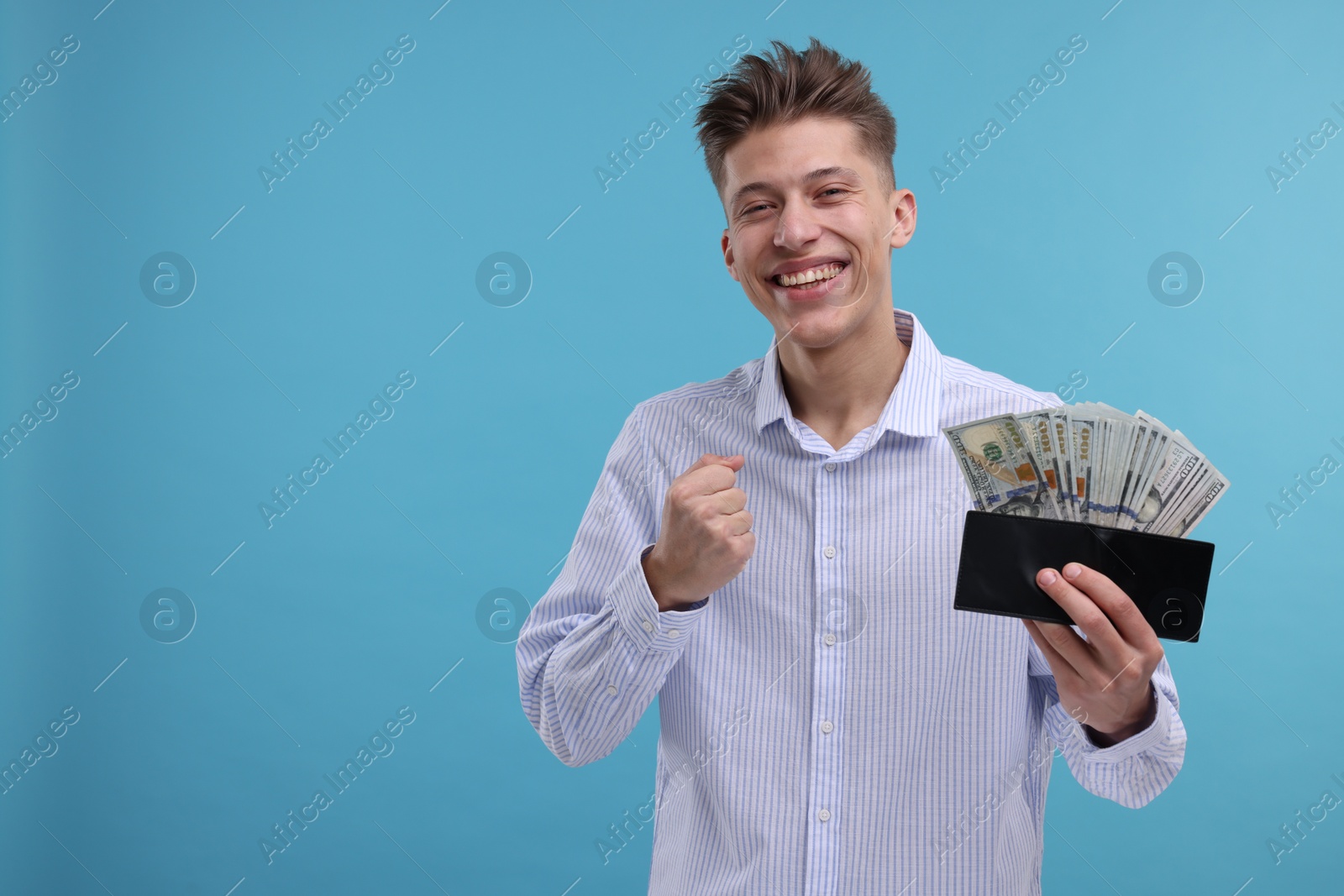 Photo of Happy man with wallet and money on light blue background. Space for text