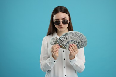 Woman with dollar banknotes on light blue background