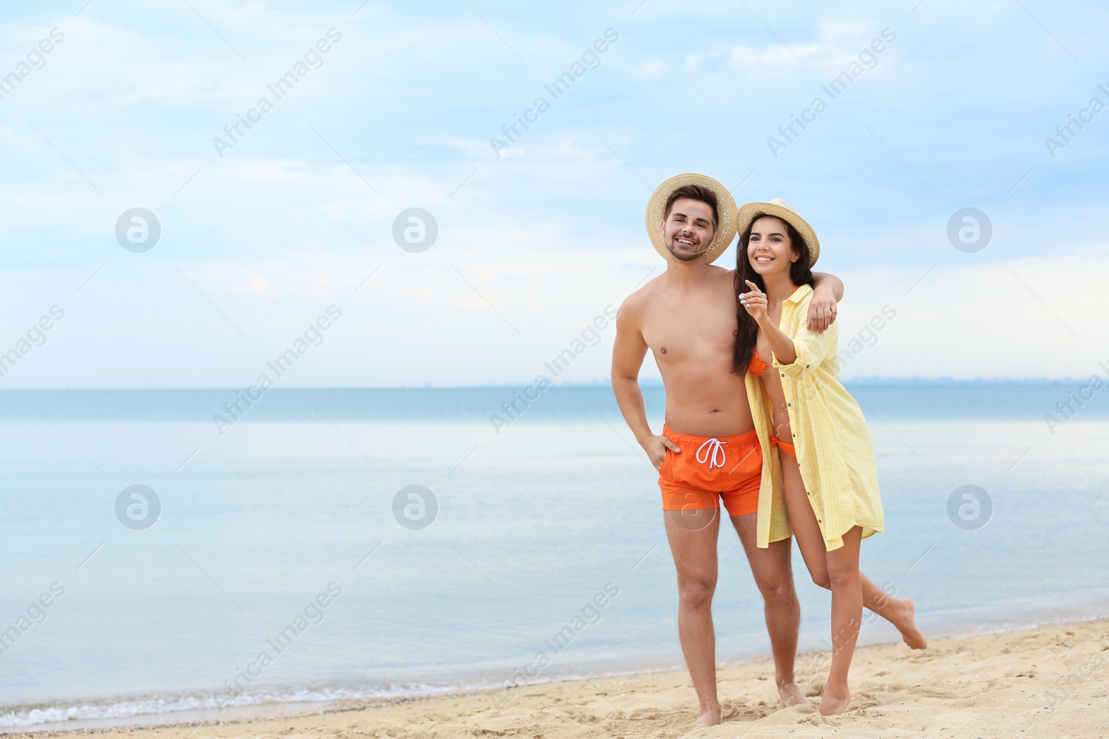 Photo of Happy young couple walking together on beach near sea