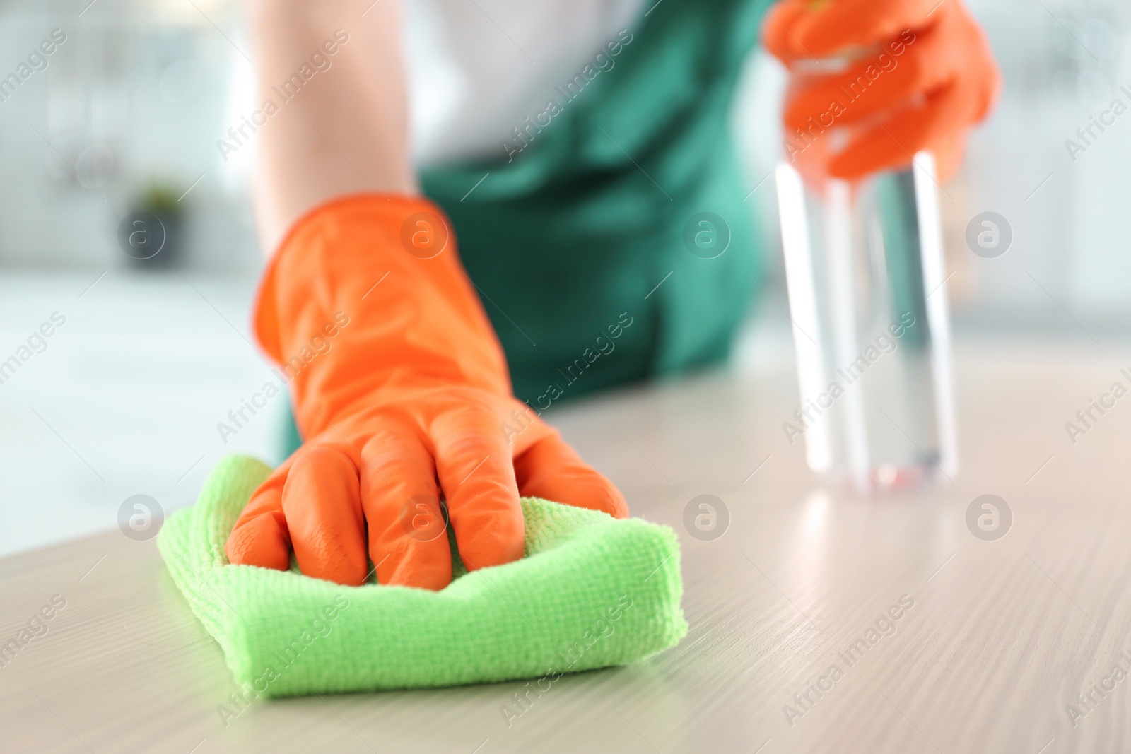 Photo of Worker in gloves cleaning table with rag, closeup. Space for text