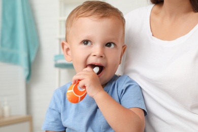 Woman and her son with toothbrush on blurred background