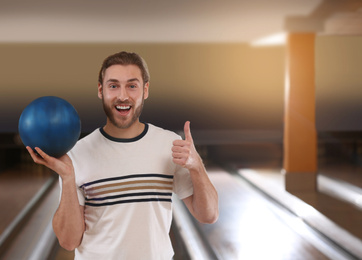 Photo of Young man with ball in bowling club. Space for text