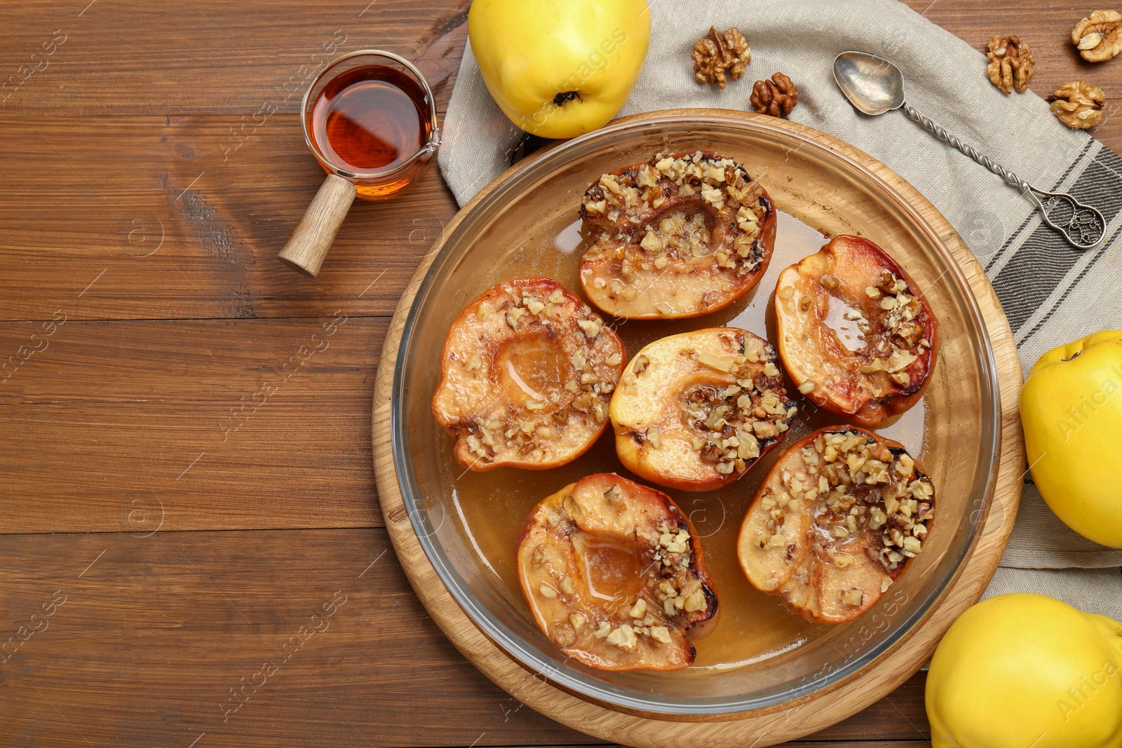 Photo of Tasty baked quinces with walnuts and honey in bowl on wooden table, flat lay. Space for text