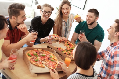 Young people having fun party with delicious pizza indoors