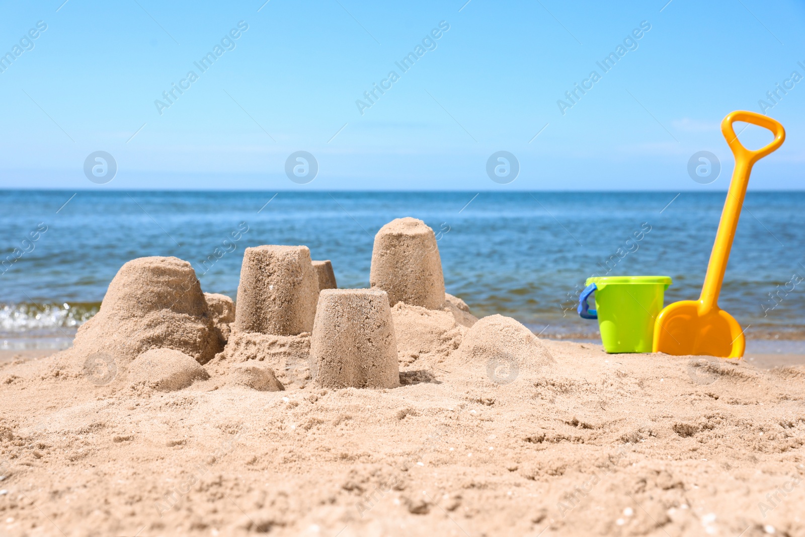 Photo of Little sand figures and plastic toys on beach near sea