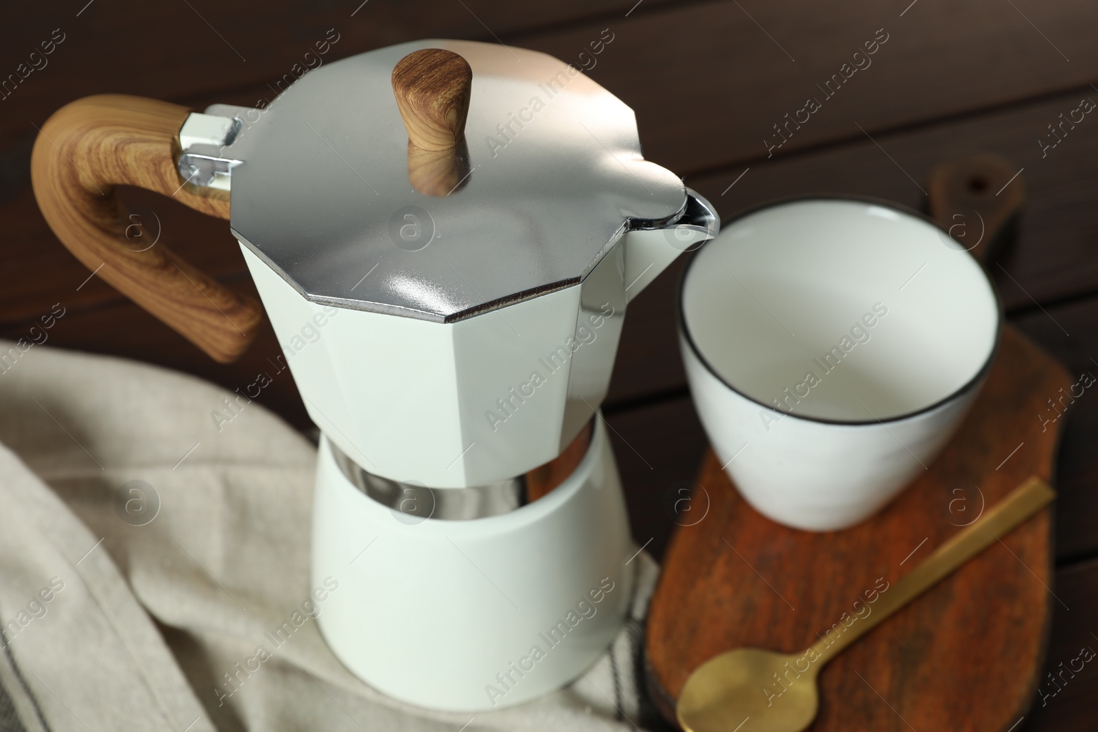 Photo of Moka pot, spoon and cup on table, closeup