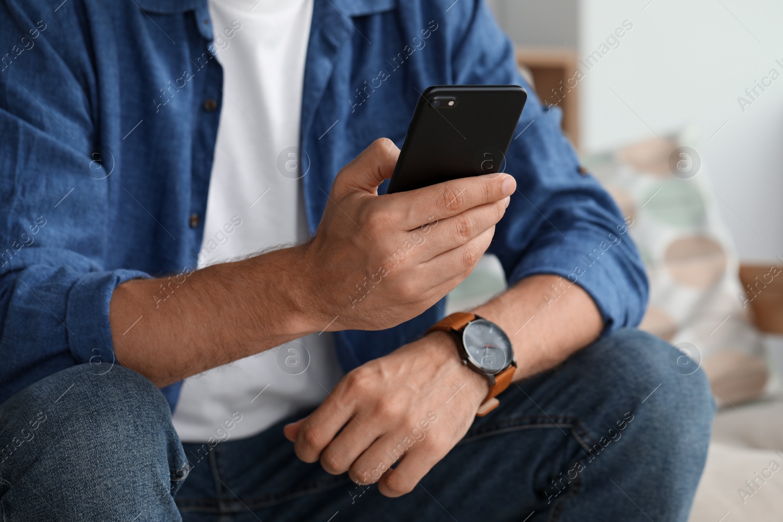 Photo of Man using smartphone at home, closeup view