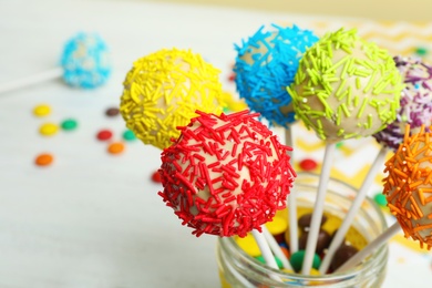 Photo of Tasty cake pops in jar on table, closeup. Space for text