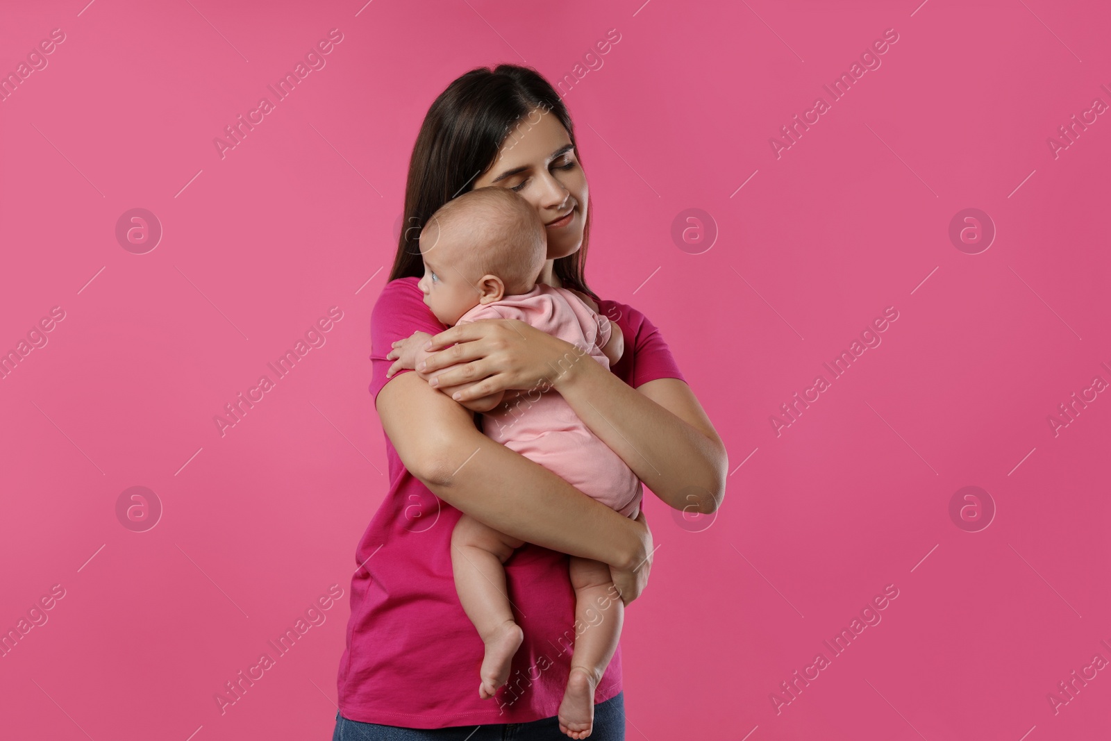 Photo of Beautiful mother with her cute baby on pink background