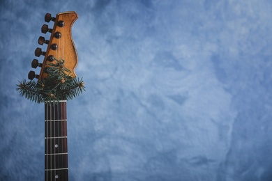 Photo of Guitar with fir tree branch on light blue background, space for text. Christmas music