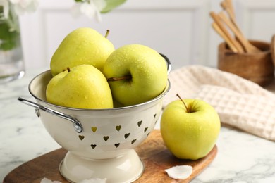 Photo of Colander with fresh apples on white marble table