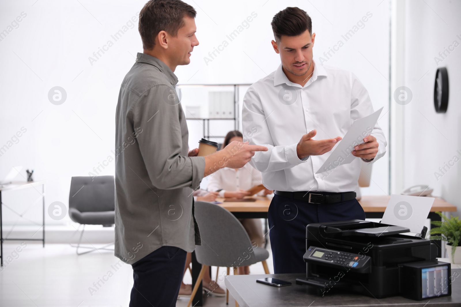 Photo of Employees near new modern printer in office