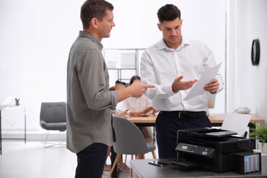 Photo of Employees near new modern printer in office