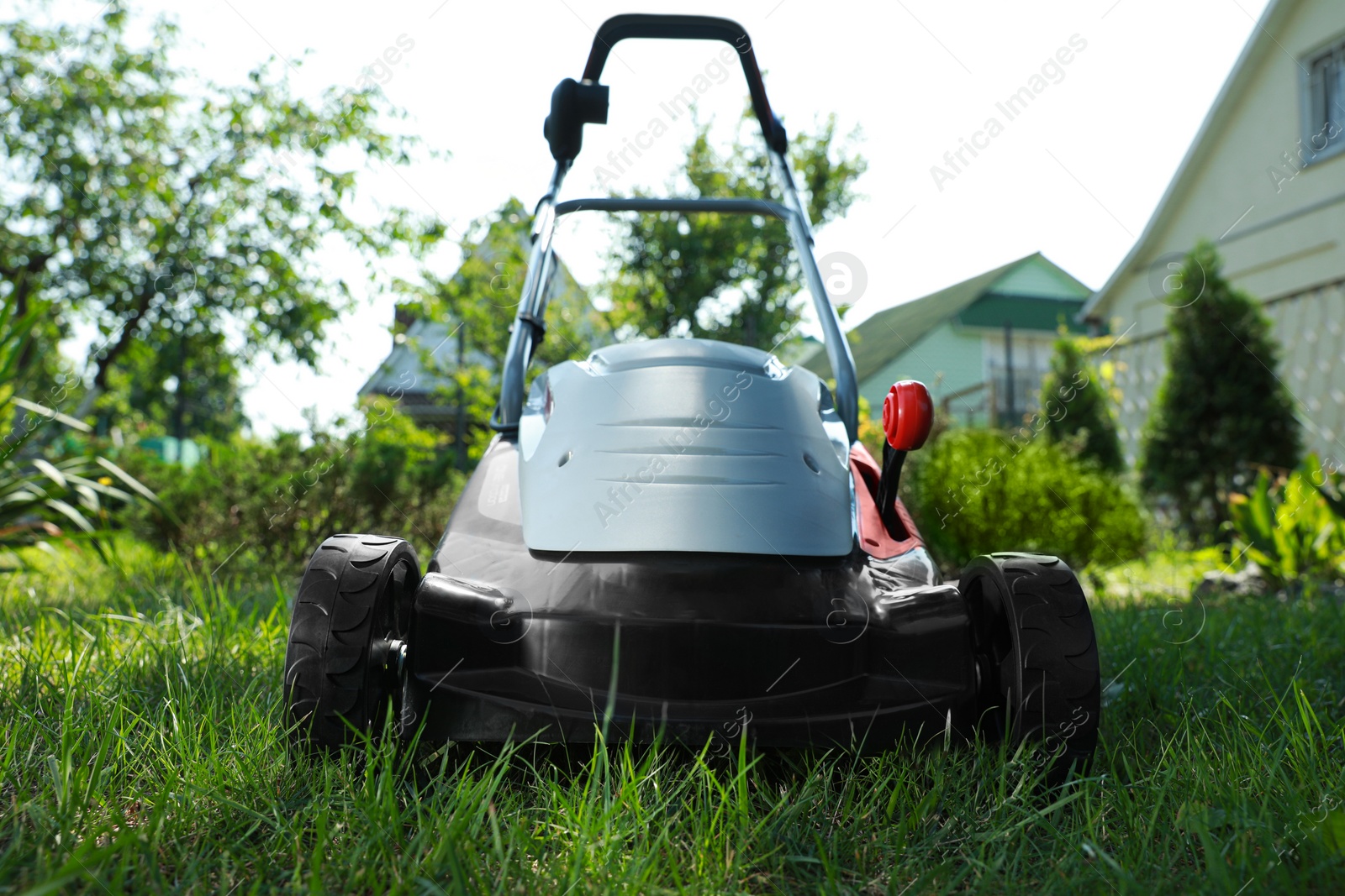 Photo of Lawn mower on green grass in garden, closeup