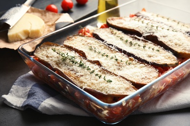 Baked eggplant with tomatoes and cheese in dishware on table, closeup