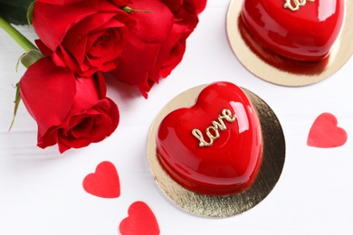 St. Valentine's Day. Delicious heart shaped cakes and beautiful roses on white wooden table, above view