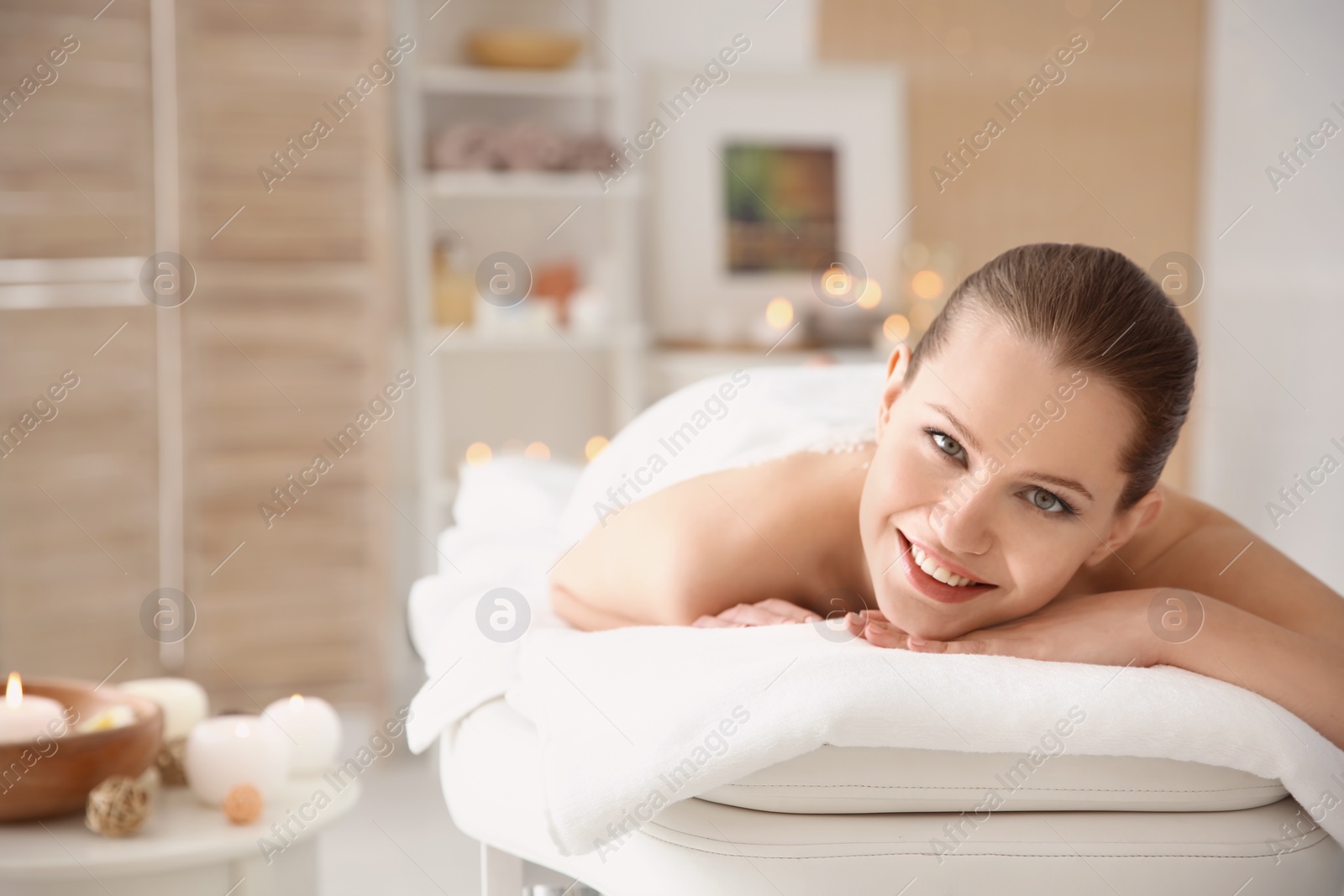 Photo of Beautiful young woman having massage with body scrub in spa salon