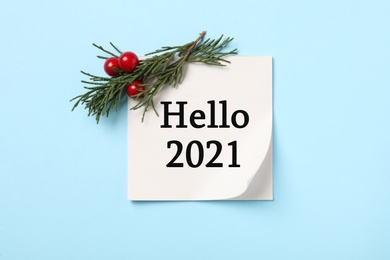 Image of Memory sticker with text Hello 2021, thuja branch and red berries on light blue background, flat lay