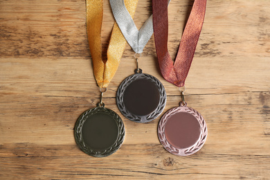 Photo of Gold, silver and bronze medals on wooden background, flat lay. Space for design