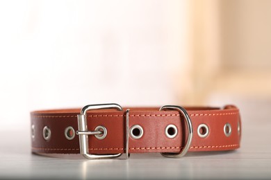 Photo of Brown leather dog collar on table against blurred background, closeup. Space for text