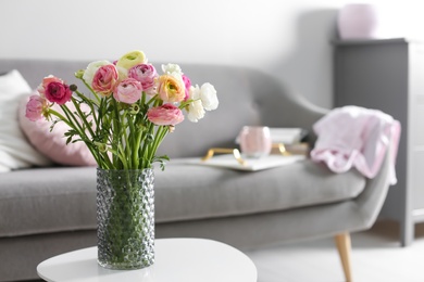 Photo of Bouquet of beautiful ranunculuses on table in living room. Space for text