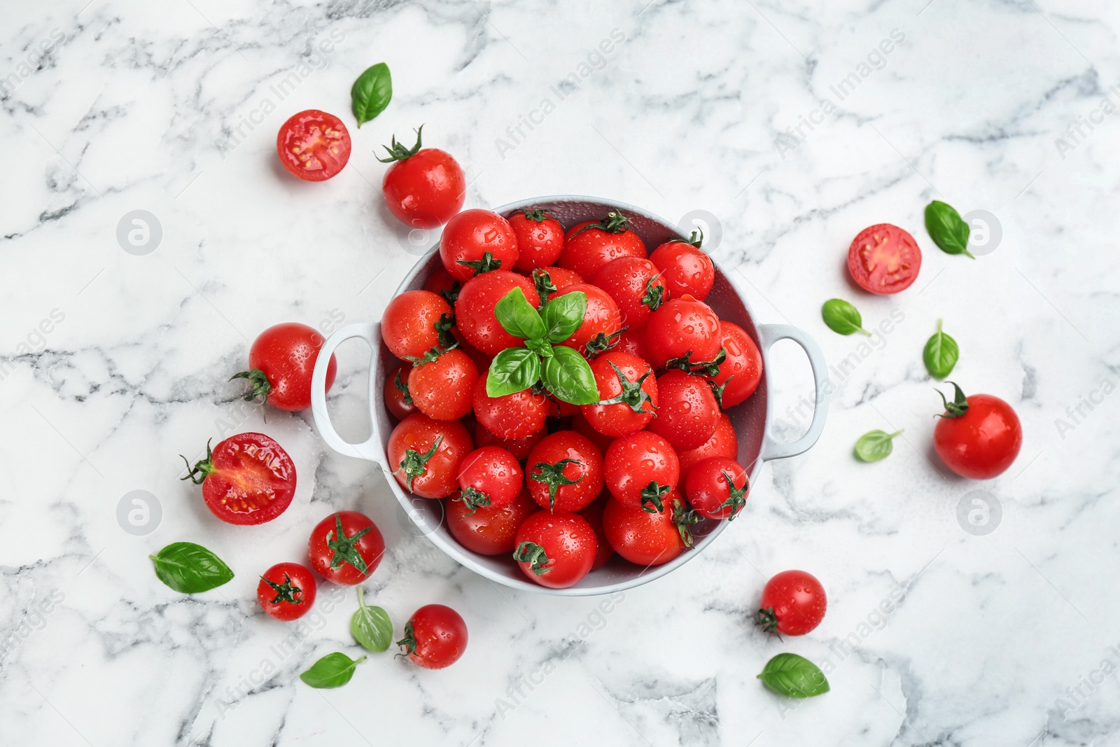 Photo of Fresh cherry tomatoes with basil leaves on white marble table, flat lay