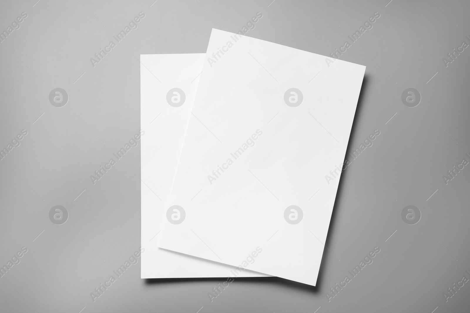 Photo of Blank paper sheets for brochure on grey background, top view. Mock up