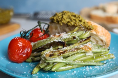 Photo of Delicious baked green beans with cheese on blue plate, closeup