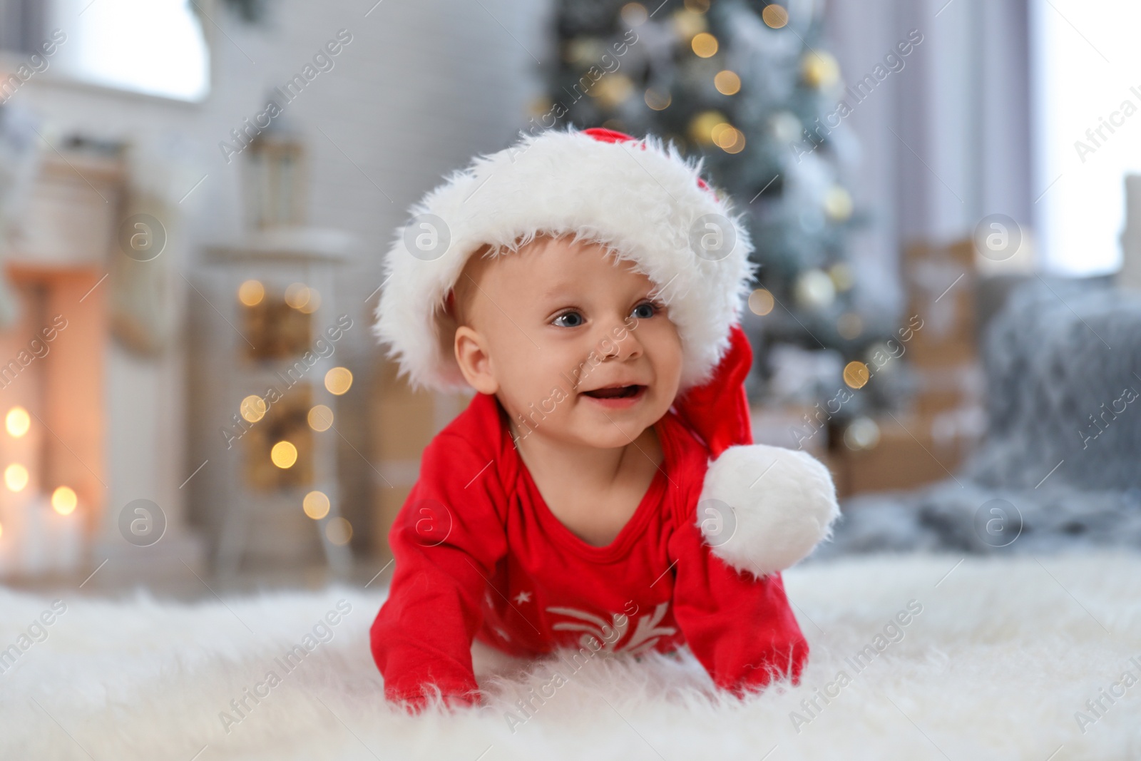 Photo of Little baby wearing Santa hat on floor at home. First Christmas