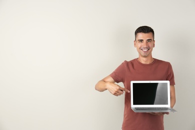 Man in casual clothes with laptop on color background