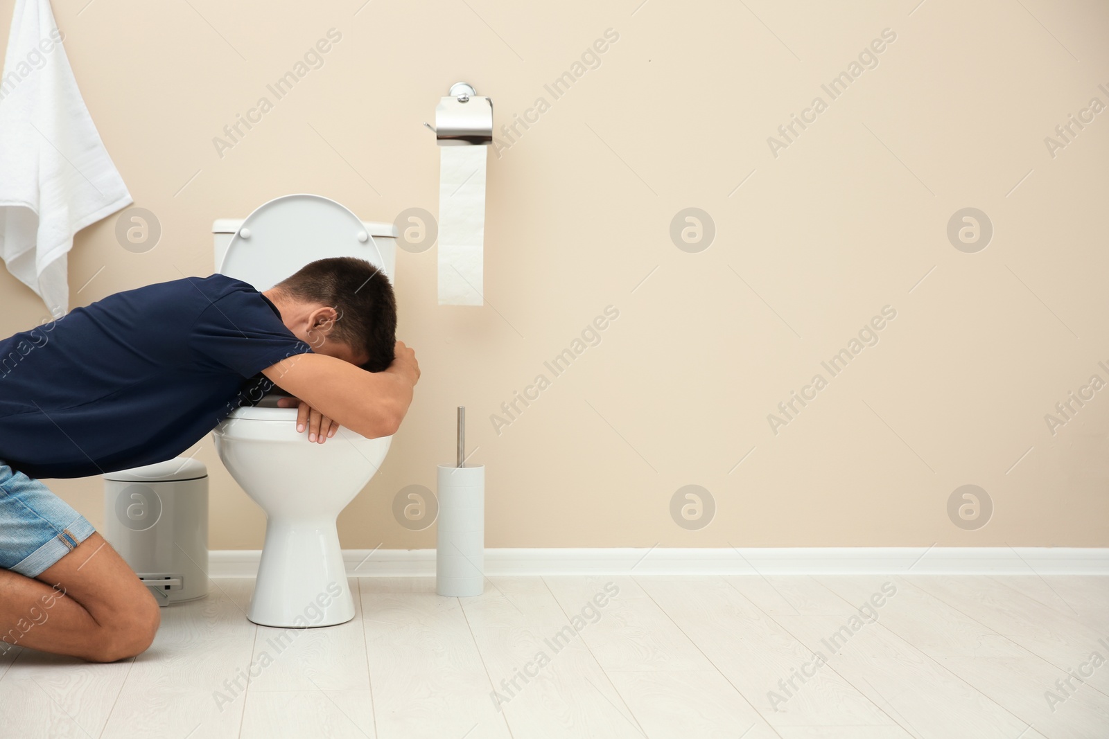 Photo of Young man vomiting in toilet bowl at home